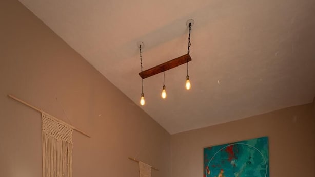 Une chambre avec un grand lit, un plancher en bois et un luminaire suspendu.