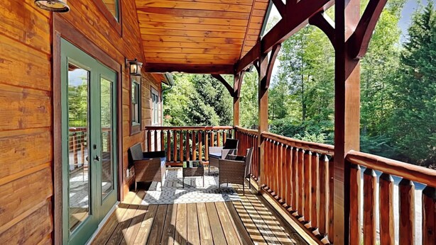 A wooden deck with outdoor furniture and a glass door leading to a covered area. - Big Sky Lodge II by Jackson Mountain Rentals (Gatlinburg)