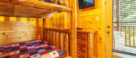 Ein gemütliches Cabin-Zimmer mit Etagenbett, einem Holzkleiderschrank und einem an der Wand befestigten Fernseher.