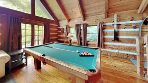 A wooden cabin with a pool table, a sofa, and a billiards rack.