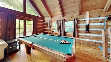 A wooden cabin with a pool table, a sofa, and a billiards rack.