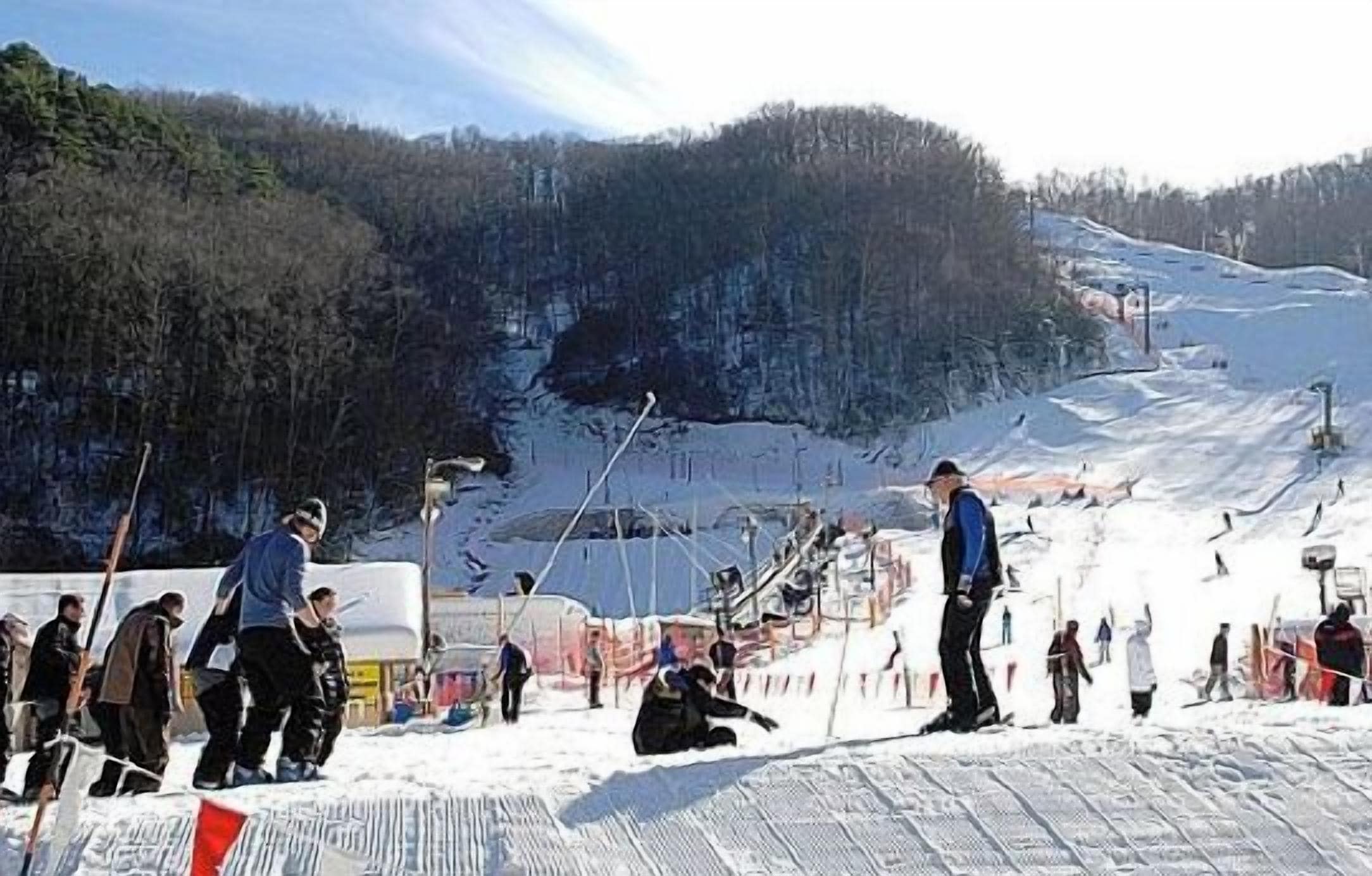 A ski slope with people skiing and standing around.