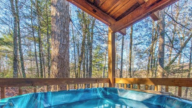 A hot tub in a wooden deck surrounded by trees.