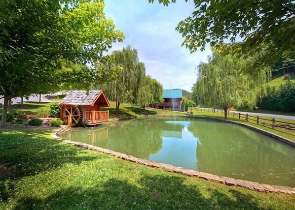 A pond with a wooden structure and a building in the background. - A Mountain Paradise by Jackson Mountain Rentals (Sevierville)