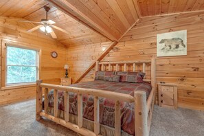 A wooden cabin bedroom with a bed, a nightstand, a clock, a window, and a ceiling fan. - A Mountain Paradise by Jackson Mountain Rentals (Sevierville)