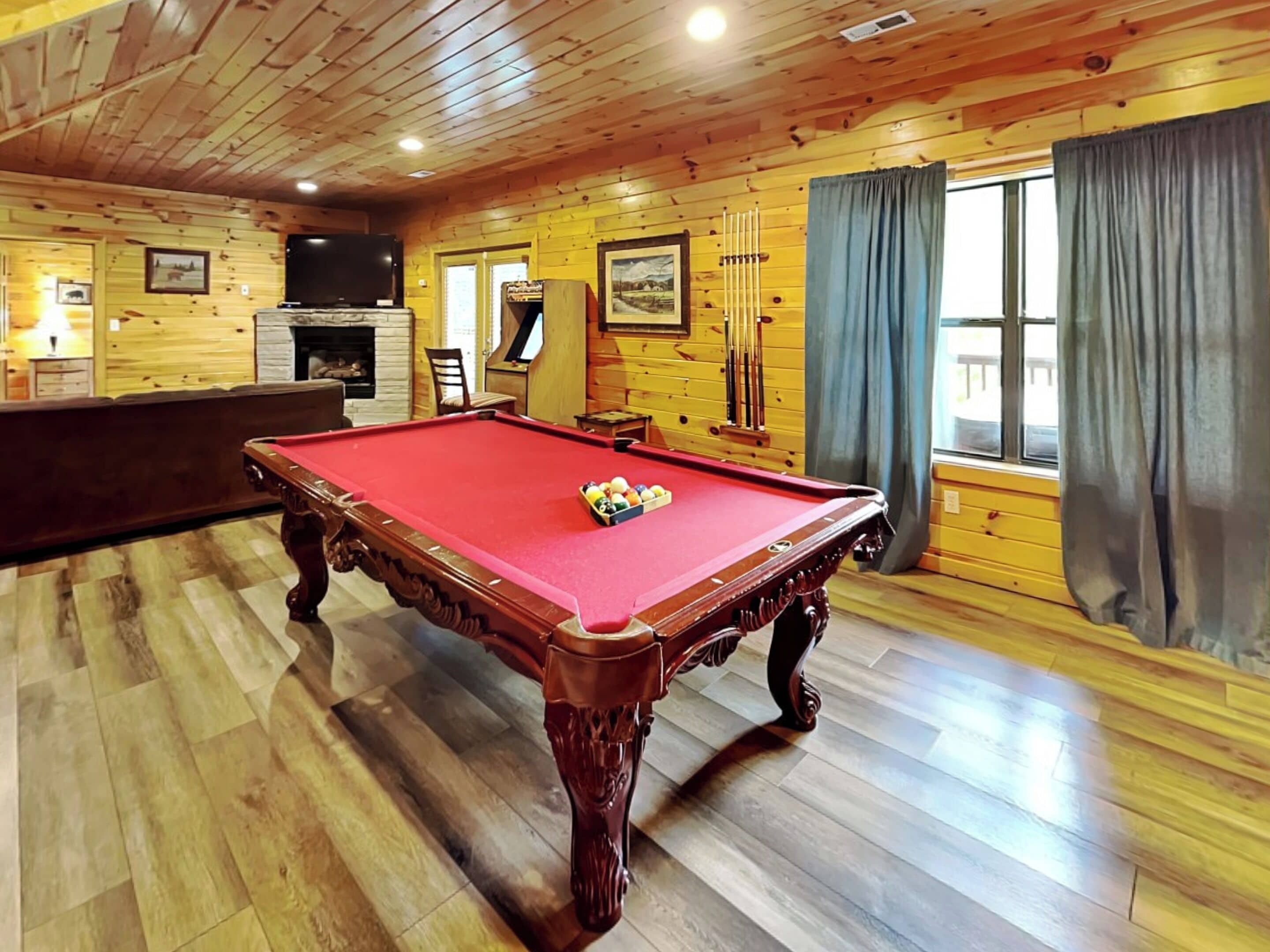 Una mesa de billar en una sala con paredes de madera y chimenea.