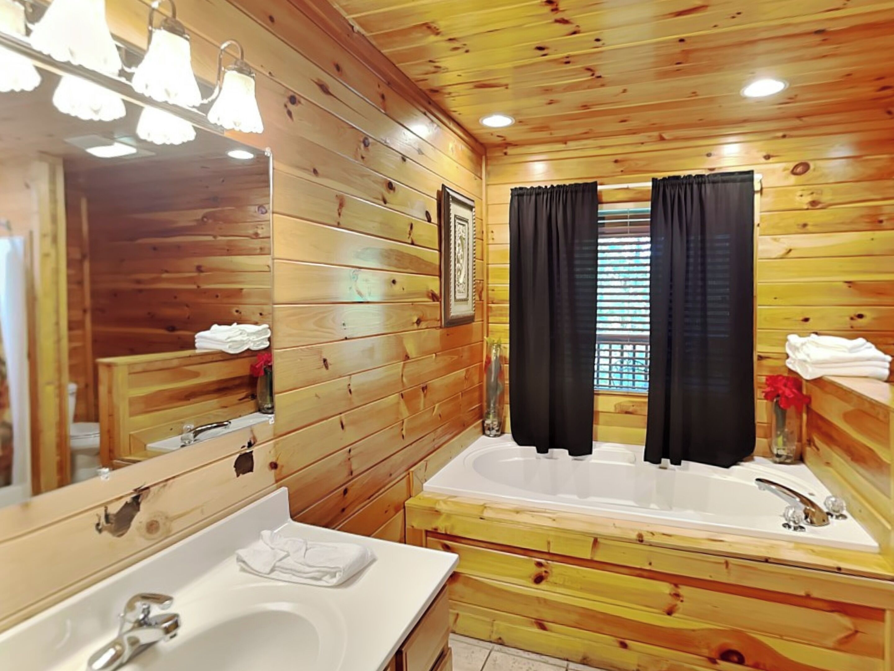 Een badkamer in chaletstijl met houten details, twee wasbakken, een grote spiegel en een bad.