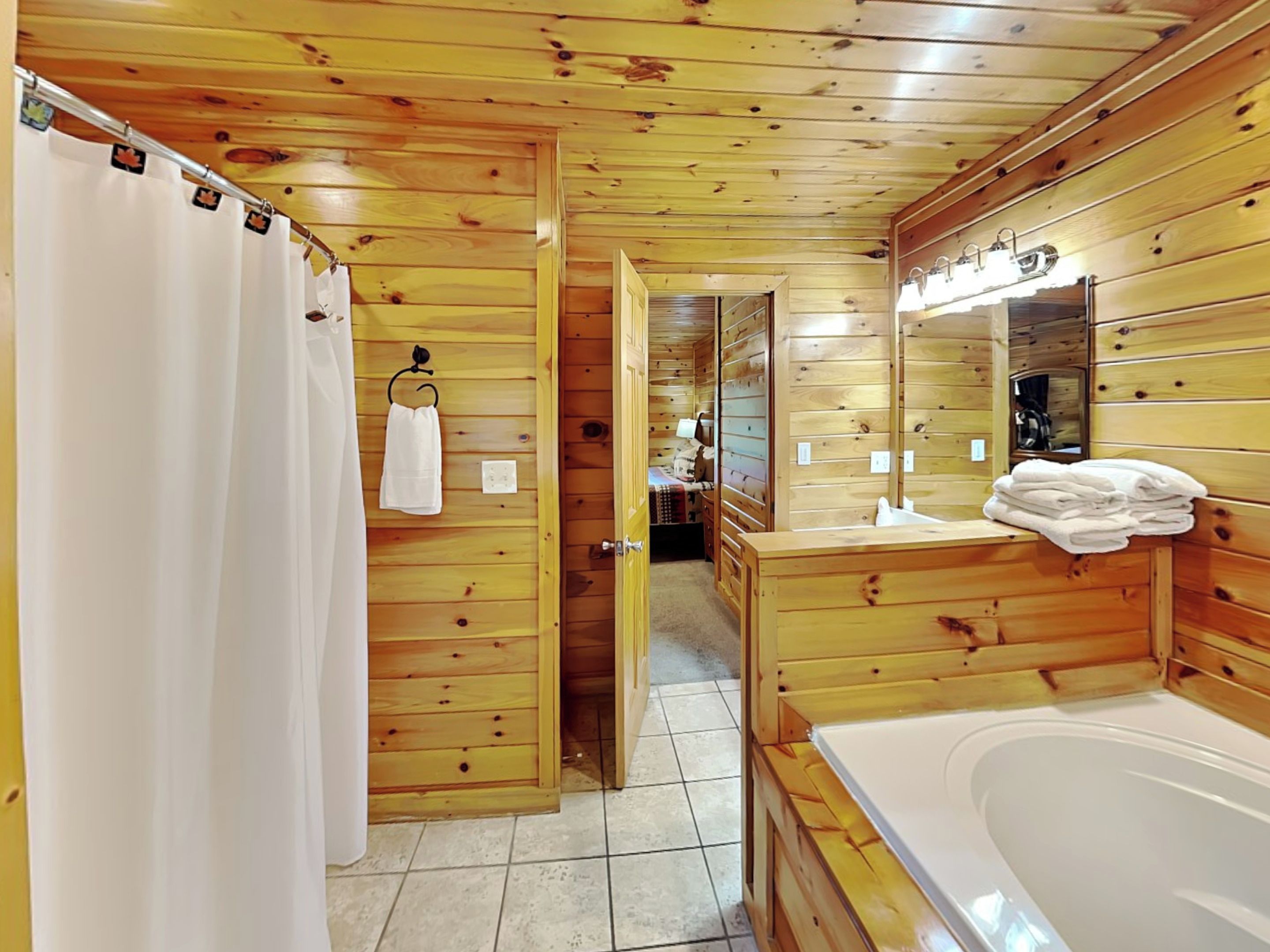 Ein Badezimmer einer Holzhütte mit Badewanne, Duschvorhang, Handtuchhalter und Spiegel.