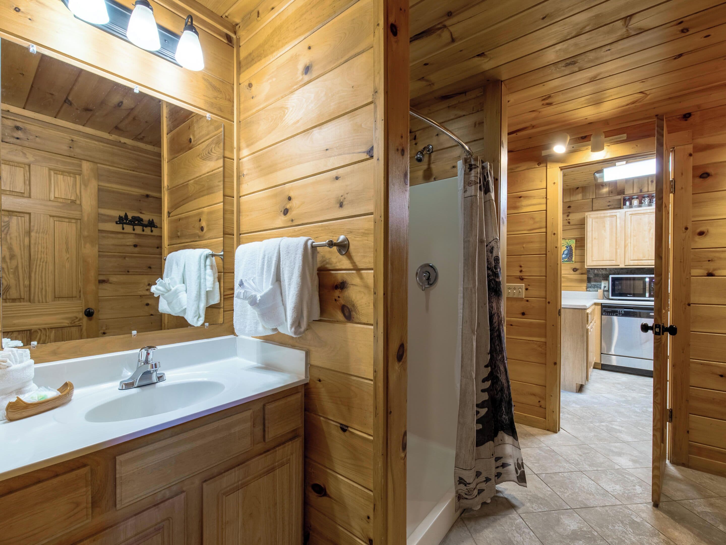 A wooden cabin bathroom with a sink, mirror, and shower.