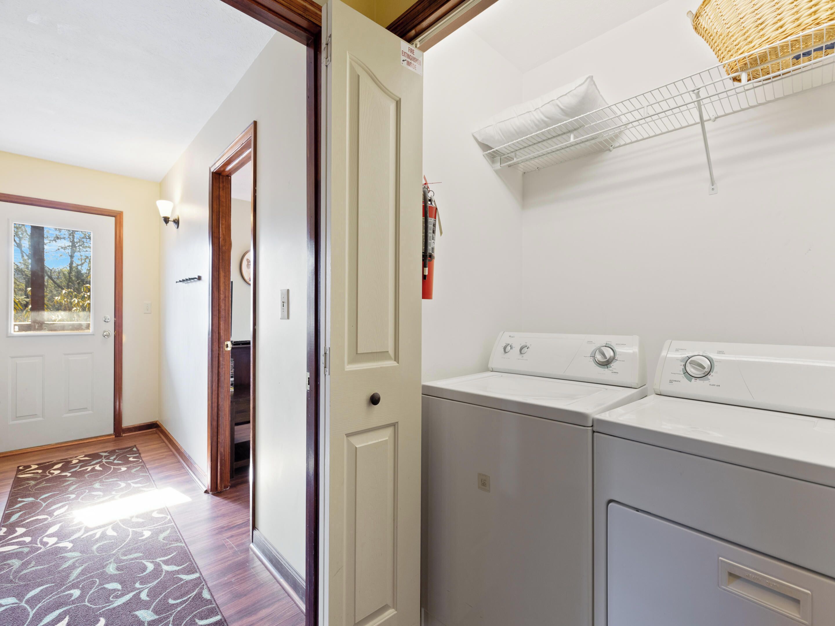 A laundry room with two washing machines, a drying rack, and a fire extinguisher.