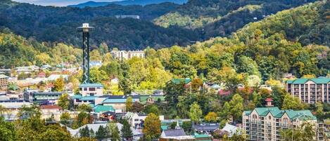 A town with a prominent tower, surrounded by lush greenery and hills.