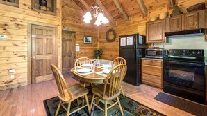L’intérieur d’une cabane en bois comprend une table à manger, des chaises, un réfrigérateur, un four à micro-ondes et une cuisinière.