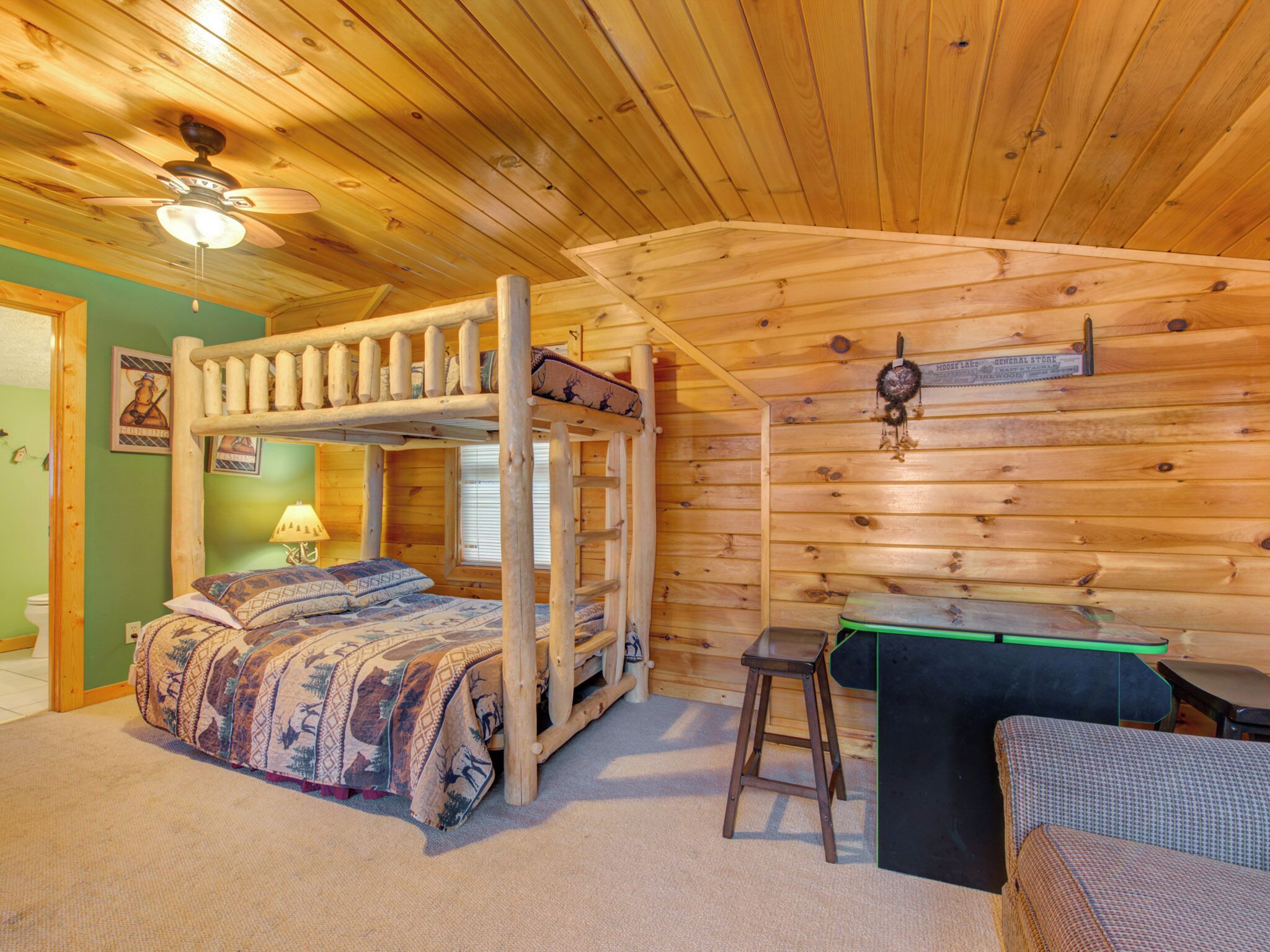 A cozy cabin room with a bunk bed, a desk, and a chair.