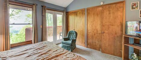 A bedroom with a large bed, a ceiling fan, a TV, and a sliding door leading to a balcony.