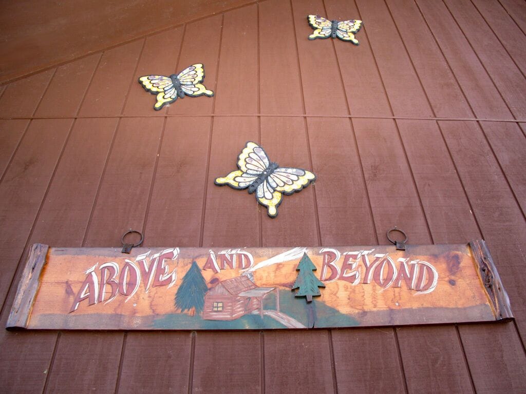 A wooden deck with a sign that reads "Above and Beyond" and decorative butterfly cutouts.