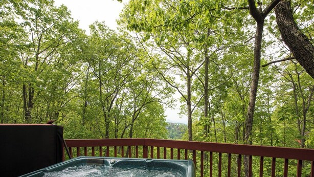 Un bain à remous sur une terrasse en bois, avec vue sur la forêt.