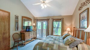 Une chambre à coucher comprenant un lit, un ventilateur de plafond, une commode, une chaise et un bureau avec un ordinateur.