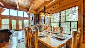 A wooden dining area with a table set for four, surrounded by wooden chairs. - A Majestic View III by Jackson Mountain Rentals (Townsend)