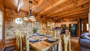 A wooden cabin interior with a dining area, kitchen, and living space. - A Majestic View III by Jackson Mountain Rentals (Townsend)