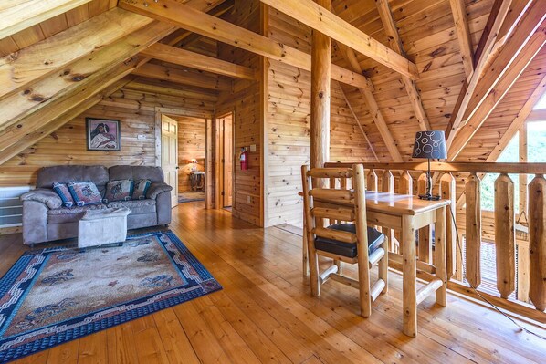 A cozy log cabin interior with a wooden ceiling, a sofa, a dining table, and a patterned rug. - A Majestic View III by Jackson Mountain Rentals (Townsend)