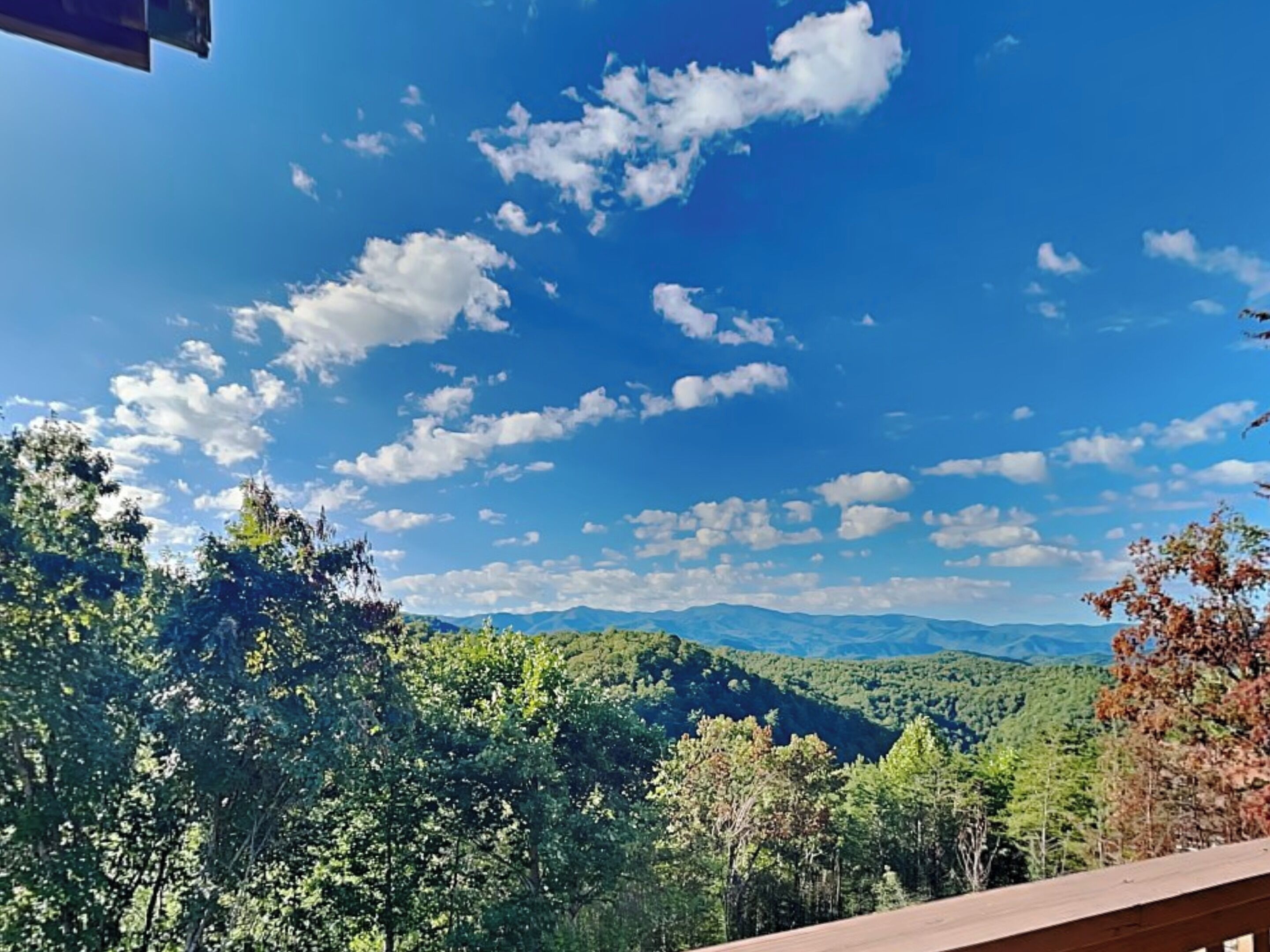 Uitzicht vanaf een balkon op een bergachtig landschap met heldere lucht.