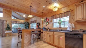 Una cocina amplia con armarios de madera, una isla central con taburetes de bar y un lavavajillas.