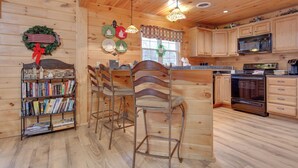 Cocina de cabaña de madera con una barra de madera, estanterías y un microondas.