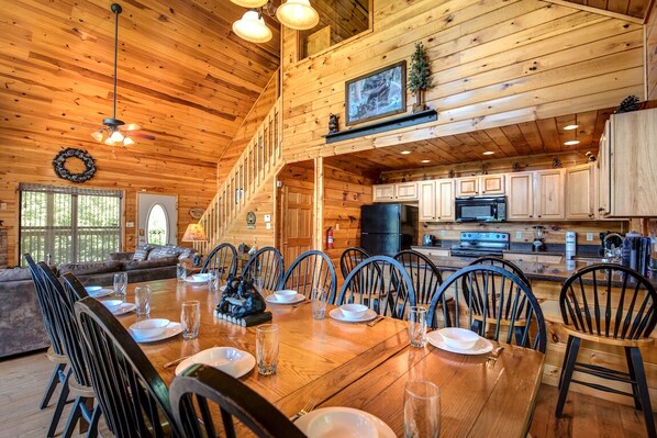 A spacious dining area with a long wooden table set for a meal, surrounded by chairs. - Bear Hunter by Jackson Mountain Rentals (Sevierville)