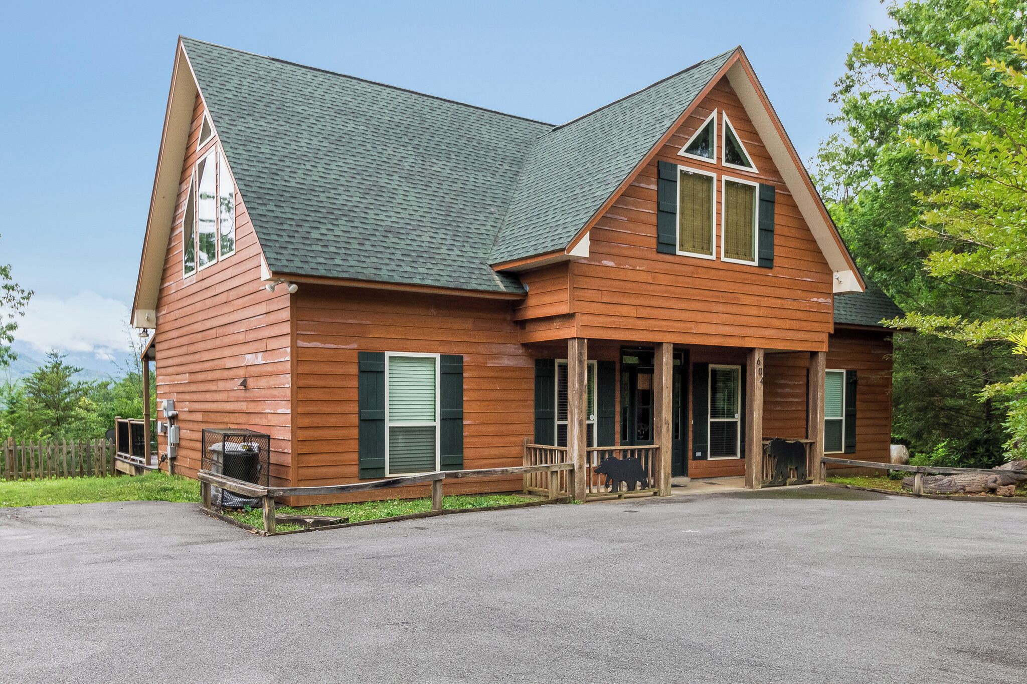 A two-story wooden cabin with a steeply pitched roof, large windows, and a porch.