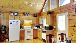 A wooden cabin-style kitchen with a refrigerator, stove, microwave, and wooden cabinets. - African Safari by Jackson Mountain Rentals (Sevierville)