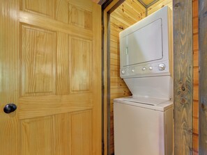 A laundry room with a wooden door and a stacked washer and dryer. - Celebration Lodge by Jackson Mountain Rentals (Gatlinburg)