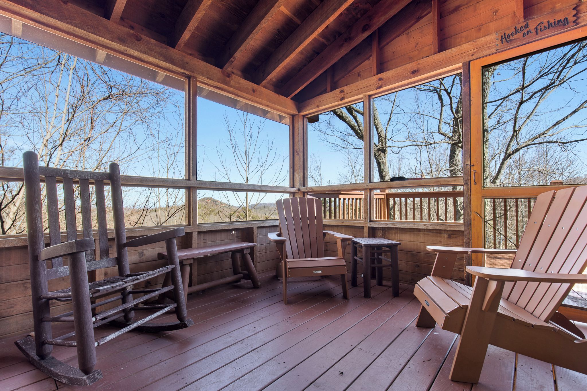 Een houten terras met Adirondack-stoelen, een bank en een tafel.