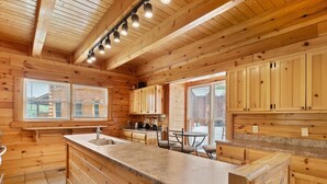 A wooden cabin kitchen with a large island, built-in cabinets, and a window overlooking the outside.