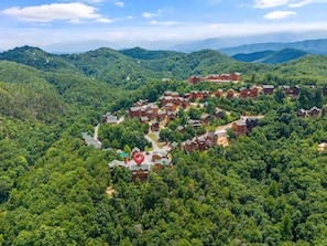 Un albergue con varias construcciones ubicado en un valle boscoso, rodeado de colinas.