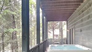 A hot tub on a wooden deck with a view of a forest. - Mountain Magic by Jackson Mountain Rentals (Sevierville)