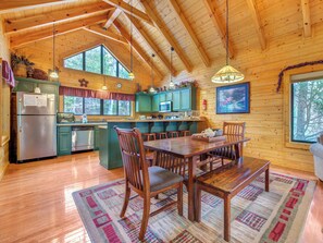 A wooden cabin interior with a kitchen, dining area, and large windows. - Mountain Magic by Jackson Mountain Rentals (Sevierville)