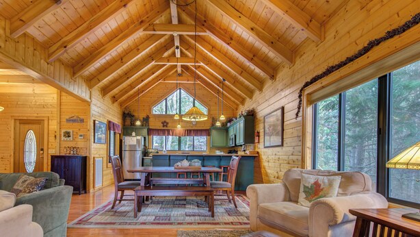 A spacious log cabin interior with a dining area, kitchen, and seating area. - Mountain Magic by Jackson Mountain Rentals (Sevierville)