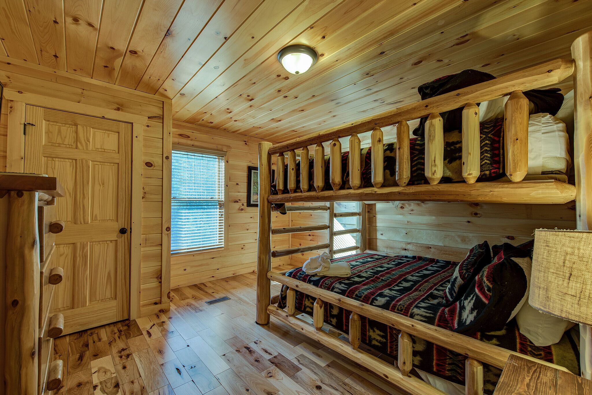 Una cabaña de madera con literas, una puerta y un ventanal.