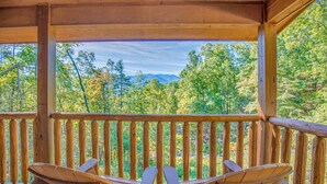 A wooden deck with two Adirondack chairs facing a forested mountain backdrop. - Rocky Top Lookout by Jackson Mountain Rentals (Gatlinburg)