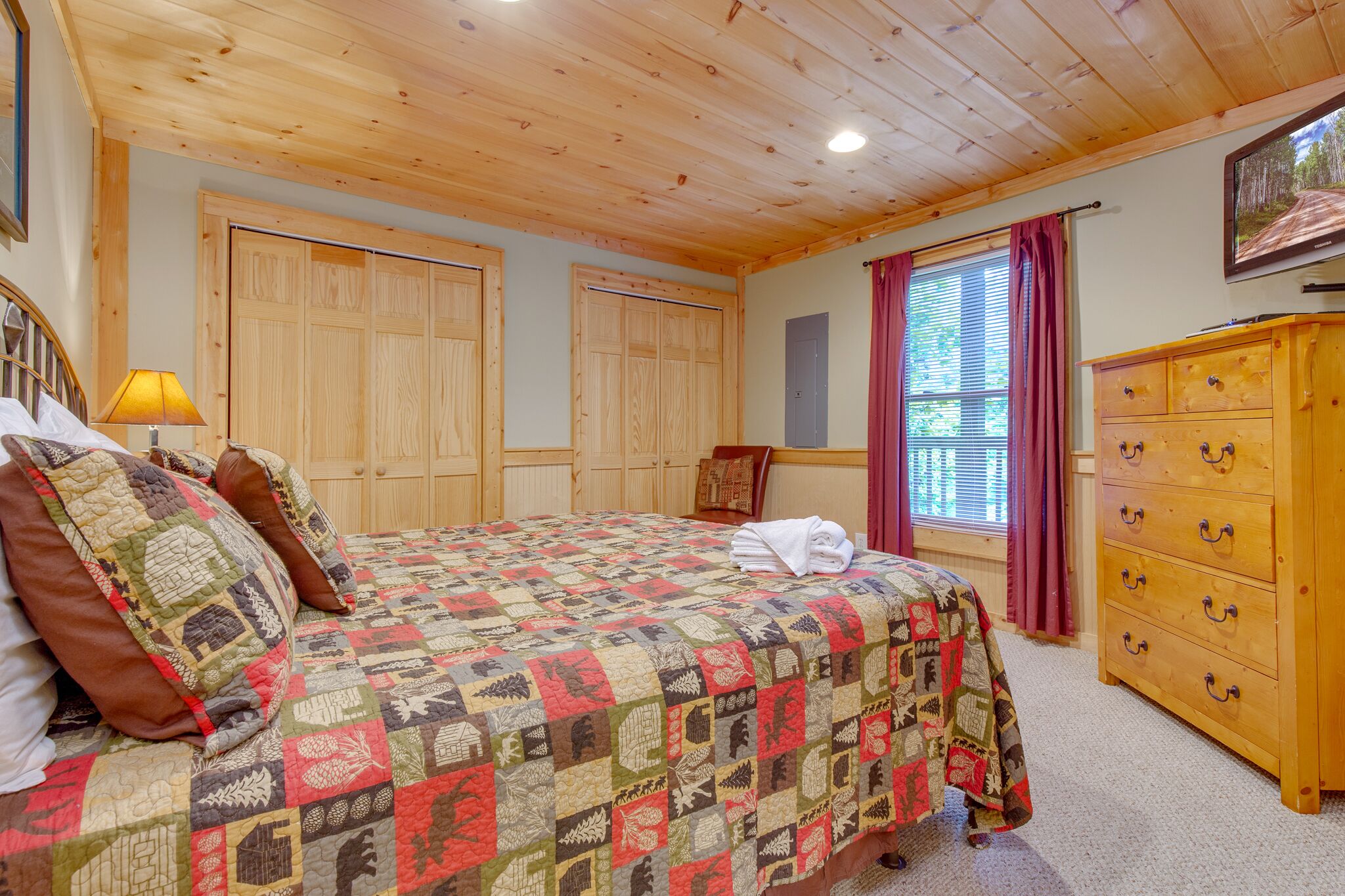Un dormitorio con colcha acolchada, armario de madera y cómoda.