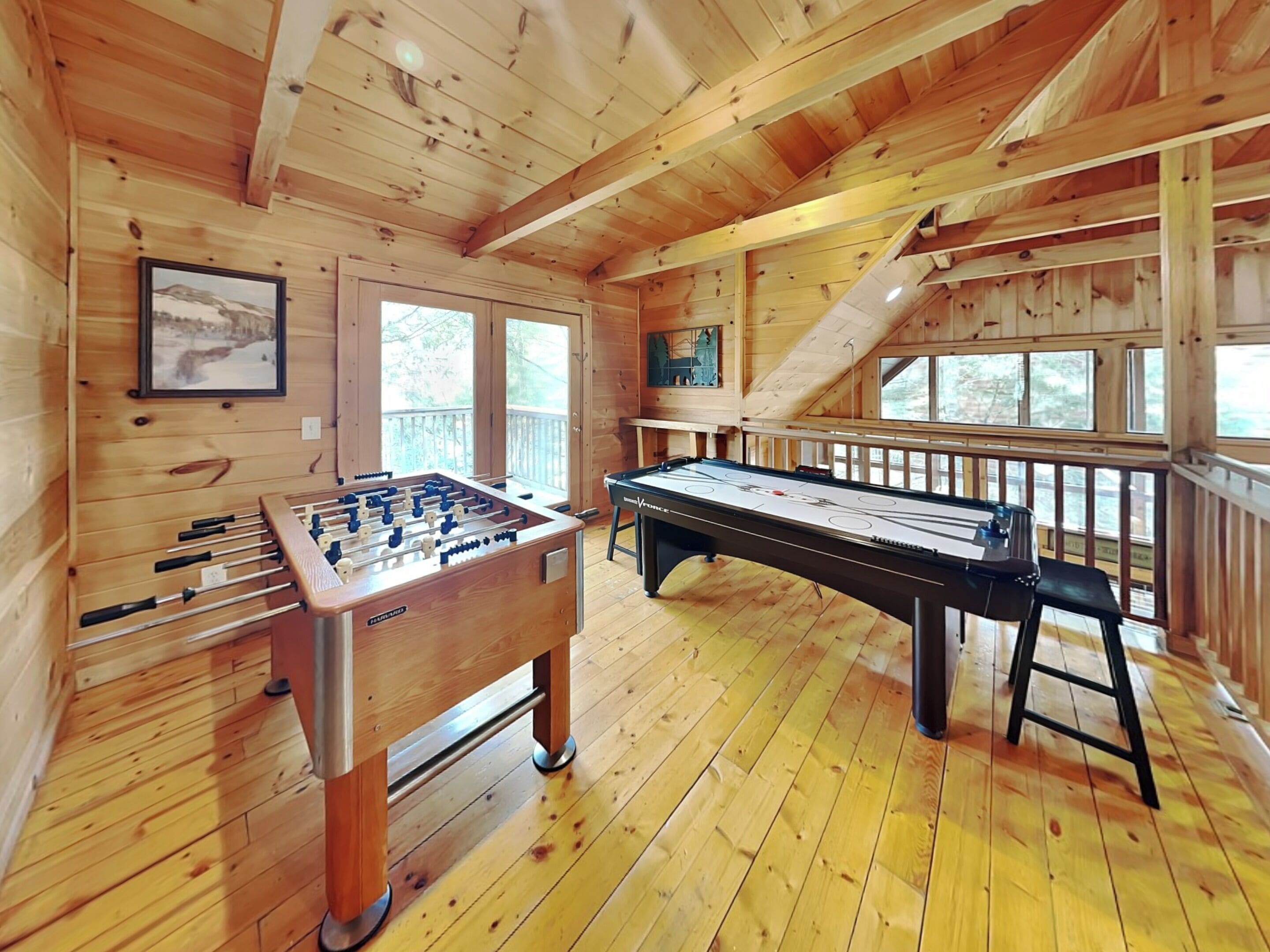 Interno di una baita in legno con un tavolo da calcio e un tavolo da cambusa.