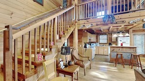 Un interior de madera con una escalera identificada con letras, una zona de cocina y un espacio para comer.