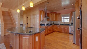 A spacious kitchen with wooden cabinets, granite countertops, and a central island with a sink.