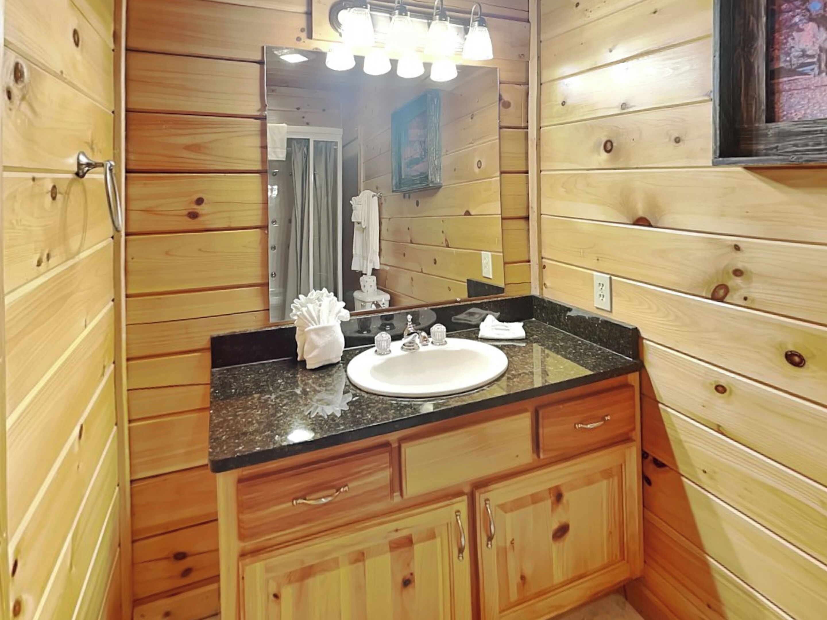 Un baño con paneles de madera, un lavamanos, un espejo y armarios.