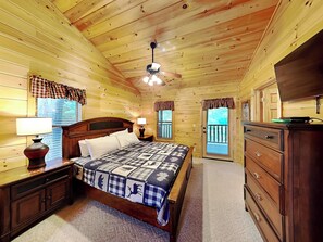 A wooden cabin bedroom with a bed, nightstands, a dresser, and a ceiling fan. - Peyton's Hideaway by Jackson Mountain Rentals (Gatlinburg)
