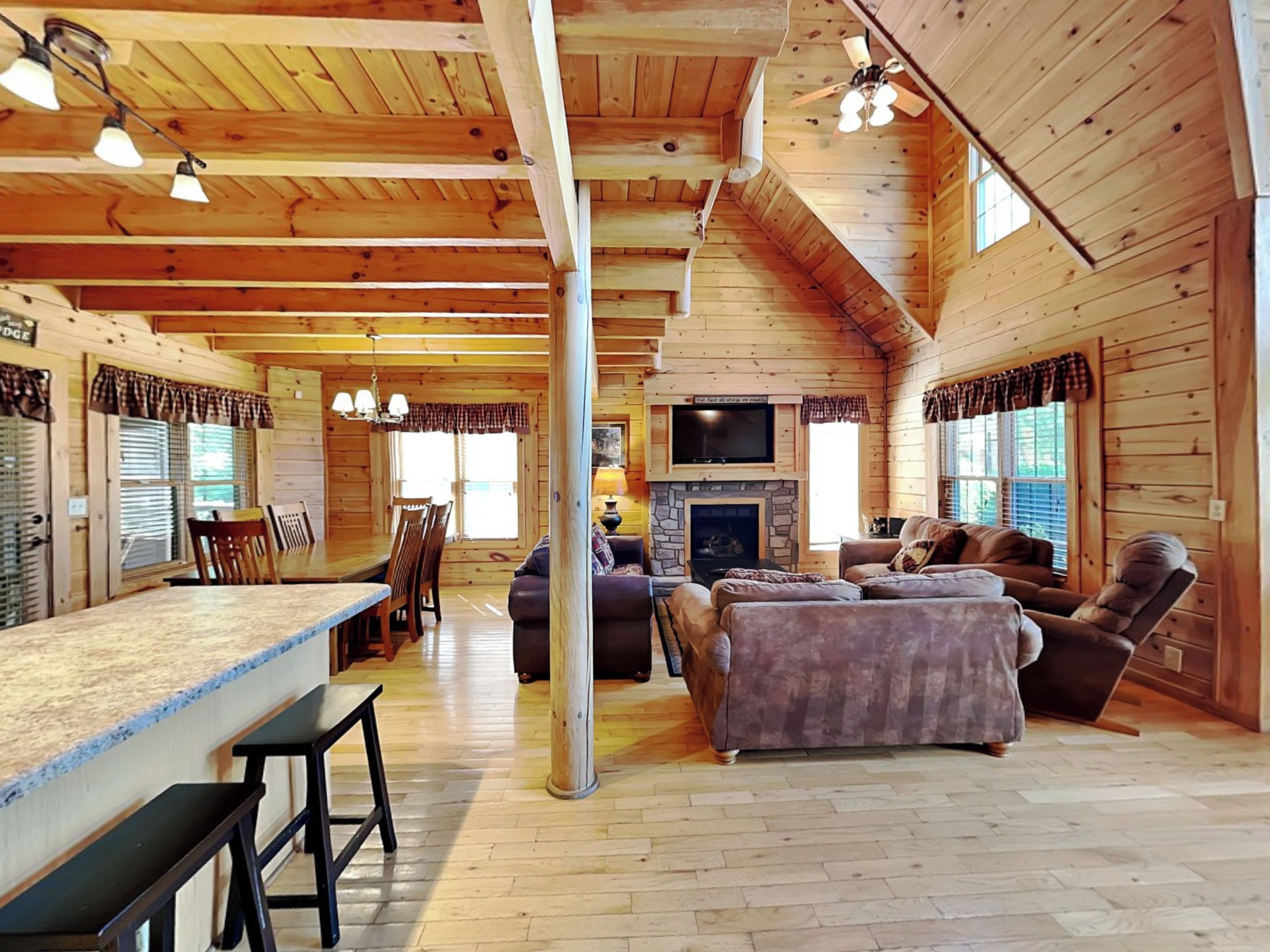 L’intérieur d’une cabane en rondins comprend un coin repas, un salon avec une cheminée et une grande fenêtre.