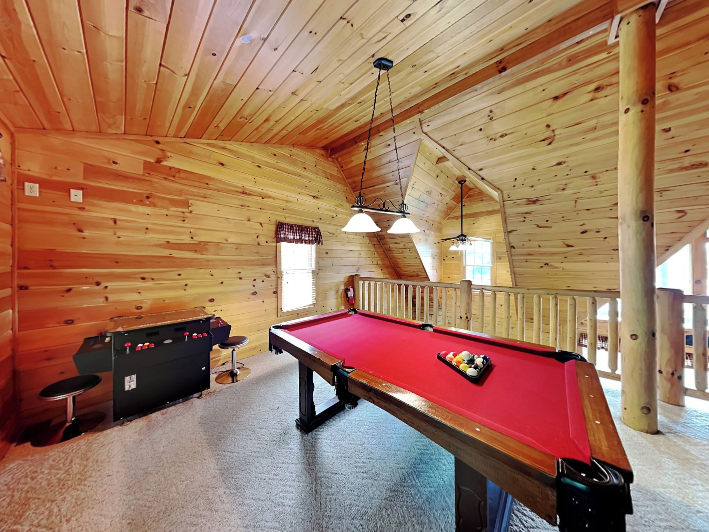 Une table de billard dans une pièce en bois, dotée d’un plafond haut et d’un petit balcon.