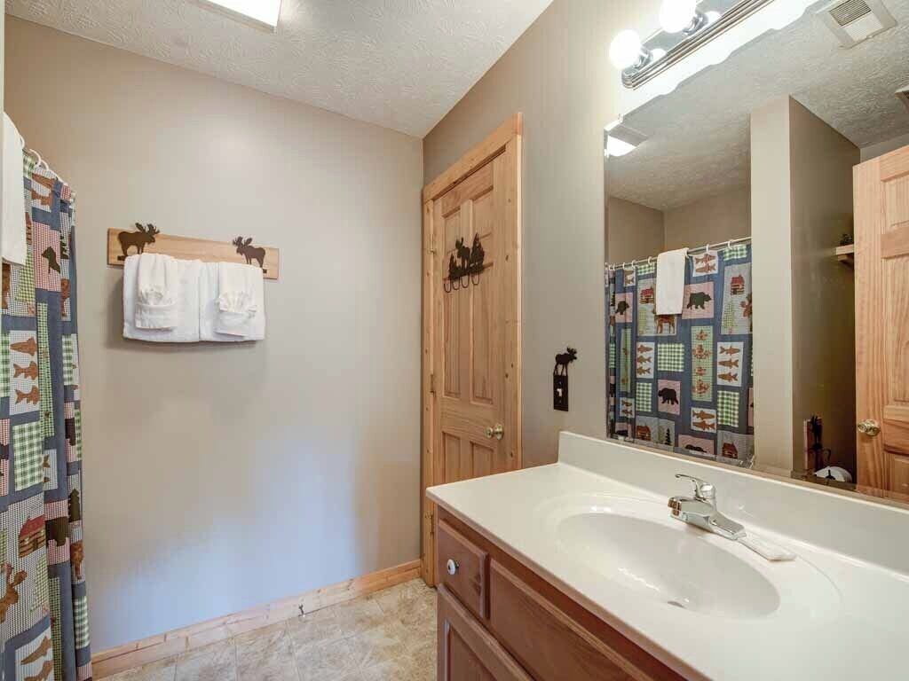 A bathroom with a wooden door, a large mirror, and a sink.