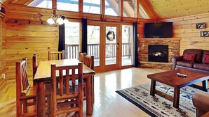 A spacious wooden cabin with a dining area, a fireplace, and a living room with a couch. - Running Bear by Jackson Mountain Rentals (Gatlinburg)