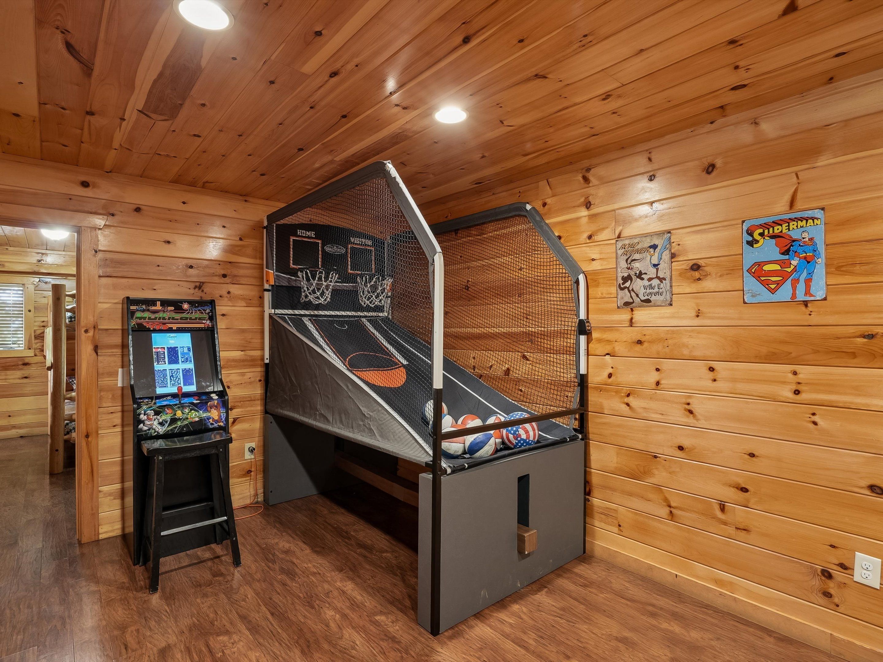 A room with a basketball arcade, wooden walls, and a ceiling with recessed lighting.